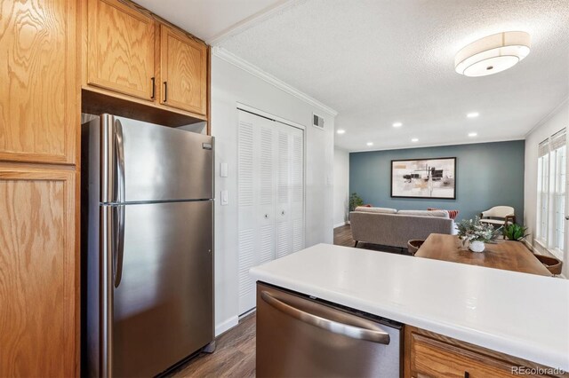 kitchen featuring open floor plan, stainless steel appliances, ornamental molding, and light countertops