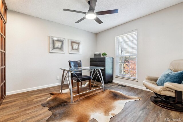 office space featuring baseboards, visible vents, a ceiling fan, dark wood finished floors, and a textured ceiling