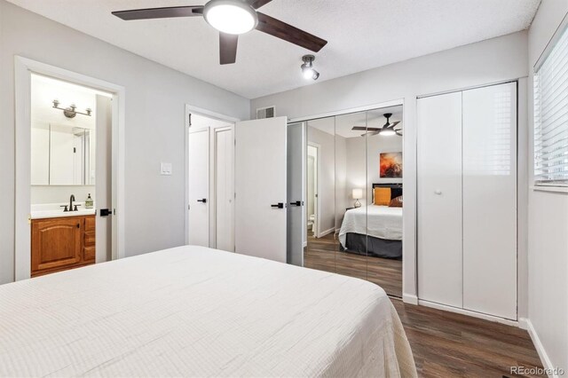 bedroom with baseboards, visible vents, dark wood-style floors, two closets, and a sink