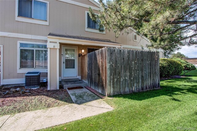 doorway to property featuring a lawn and central AC unit