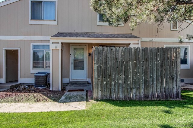 property entrance featuring central AC unit and a lawn