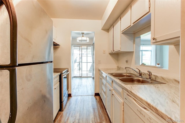 kitchen with a wealth of natural light, white cabinetry, sink, stainless steel appliances, and light hardwood / wood-style flooring