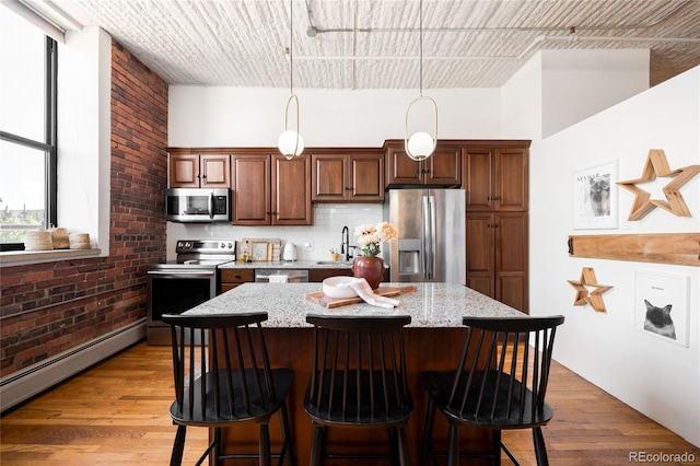 2261 Blake St Unit 2G, Denver, CO 80205 - kitchen with stainless steel appliances, a kitchen bar, a center island, baseboard heating, and tasteful backsplash