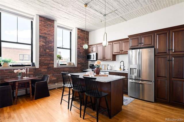 2261 Blake St Unit 2G, Denver, CO 80205 - kitchen featuring stainless steel appliances, a sink, a center island, a kitchen bar, and light wood finished floors