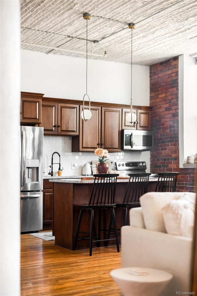 2261 Blake St Unit 2G, Denver, CO 80205 - kitchen featuring stainless steel appliances, a kitchen breakfast bar, light countertops, and tasteful backsplash