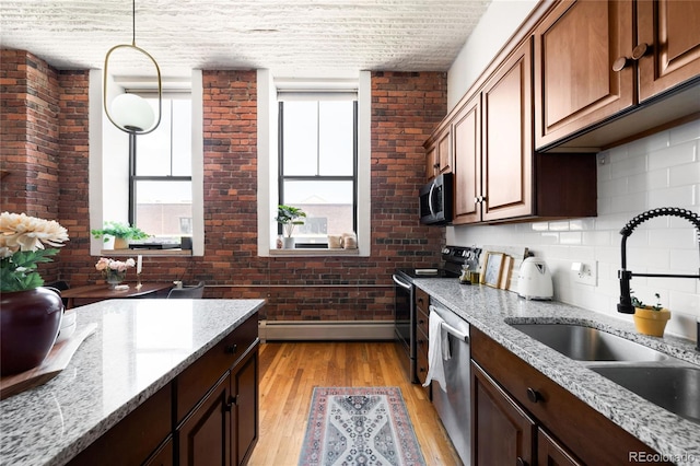 2261 Blake St Unit 2G, Denver, CO 80205 - kitchen featuring appliances with stainless steel finishes, a sink, baseboard heating, baseboards, and light wood-style floors