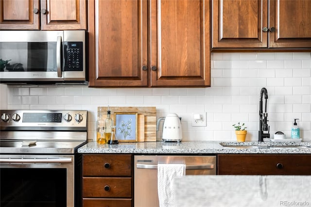 2261 Blake St Unit 2G, Denver, CO 80205 - kitchen with appliances with stainless steel finishes, a sink, tasteful backsplash, light stone counters, and dark brown cabinets