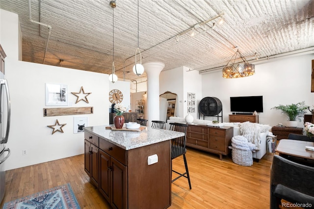 2261 Blake St Unit 2G, Denver, CO 80205 - kitchen featuring a breakfast bar area, open floor plan, pendant lighting, and light wood finished floors