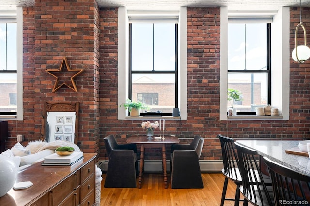 2261 Blake St Unit 2G, Denver, CO 80205 - dining room featuring light wood finished floors, baseboard heating, and brick wall