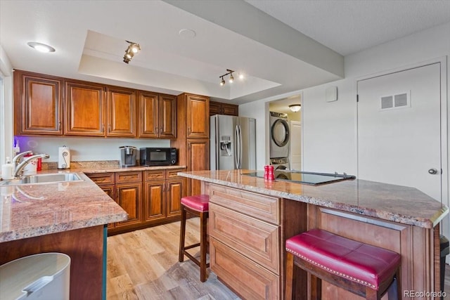 kitchen with sink, a tray ceiling, black appliances, and light stone countertops