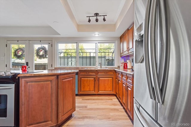 kitchen with stainless steel fridge with ice dispenser, sink, a raised ceiling, and a healthy amount of sunlight