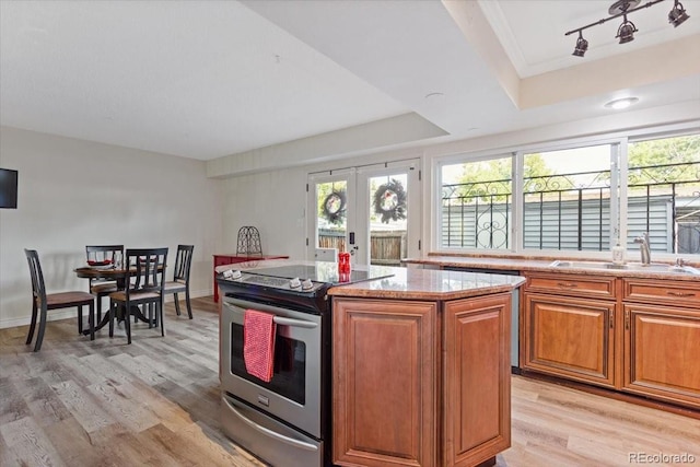 kitchen with electric stove, light hardwood / wood-style floors, a center island, and sink