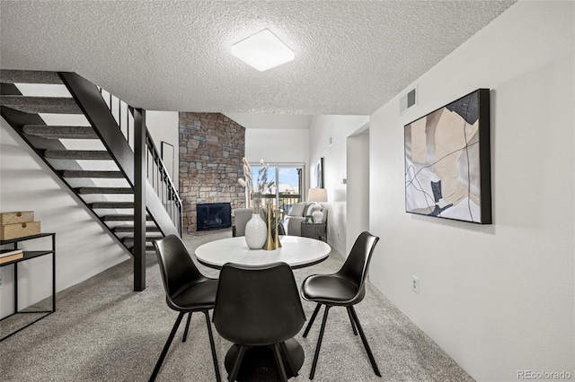 dining space with a fireplace, a textured ceiling, and light carpet