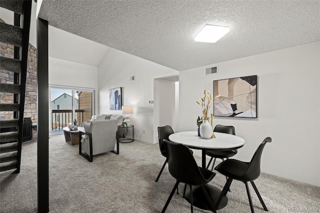 carpeted dining room with lofted ceiling and a textured ceiling