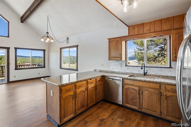 kitchen with lofted ceiling with beams, a sink, stainless steel appliances, a peninsula, and backsplash