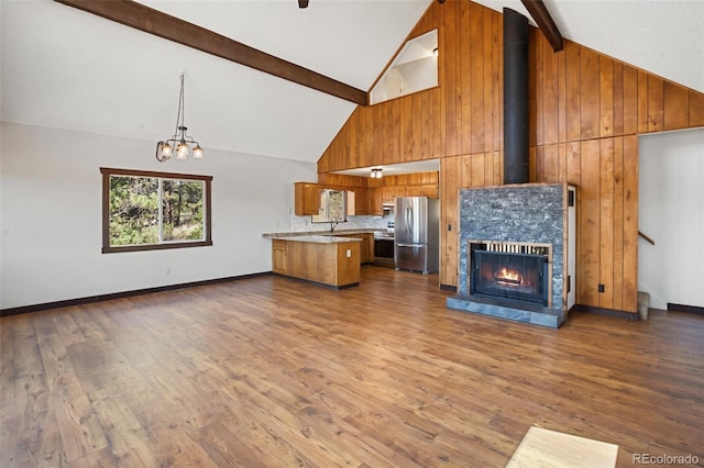 unfurnished living room featuring dark wood-type flooring, wooden walls, high vaulted ceiling, and beamed ceiling