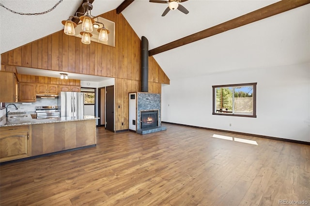 kitchen with brown cabinets, high vaulted ceiling, stainless steel appliances, open floor plan, and under cabinet range hood