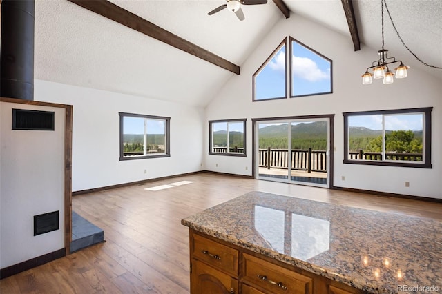 unfurnished living room with wood finished floors, beam ceiling, baseboards, ceiling fan, and high vaulted ceiling
