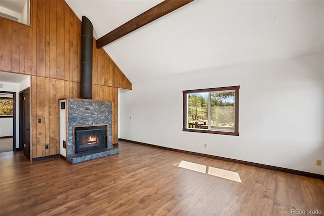 unfurnished living room with a healthy amount of sunlight, high vaulted ceiling, dark wood finished floors, and beam ceiling