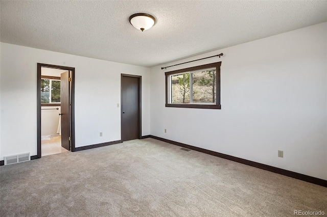 unfurnished bedroom with light colored carpet, a textured ceiling, visible vents, and baseboards