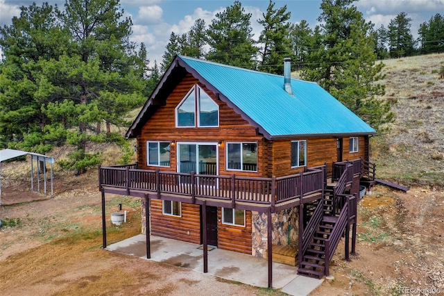 back of house featuring metal roof, a wooden deck, a patio area, log exterior, and stairs