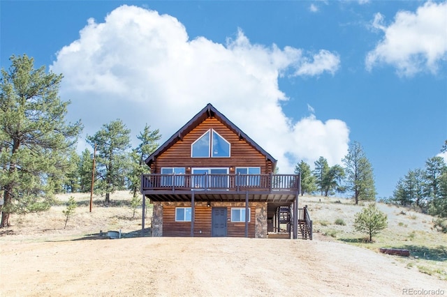 view of front of house with log siding, stairs, a deck, and dirt driveway