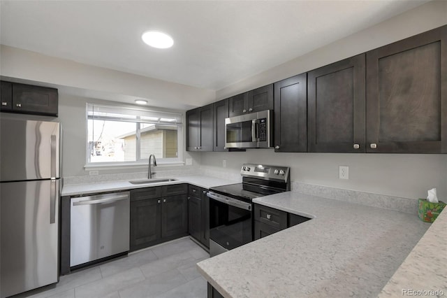 kitchen with dark brown cabinets, sink, light stone countertops, and stainless steel appliances