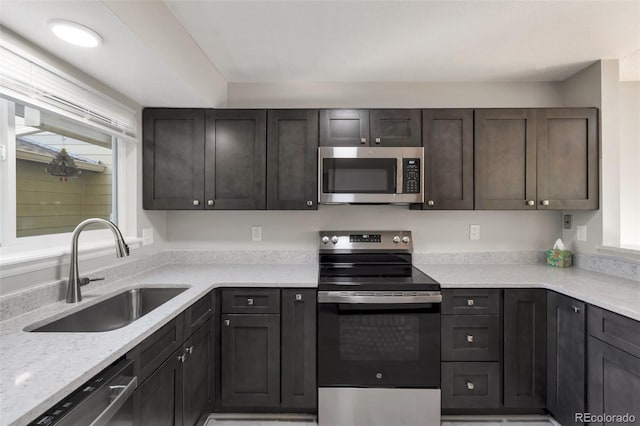 kitchen featuring dark brown cabinets, sink, light stone counters, and stainless steel appliances