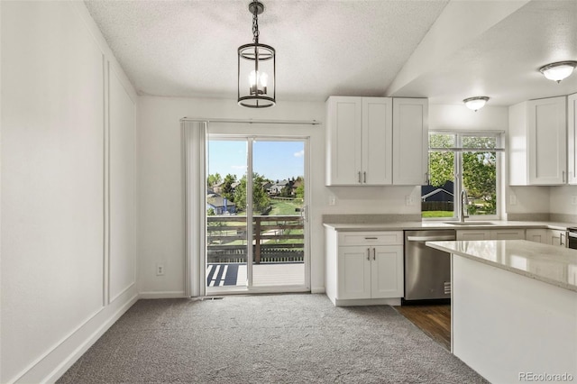 kitchen with stainless steel dishwasher, a sink, a textured ceiling, white cabinetry, and healthy amount of natural light