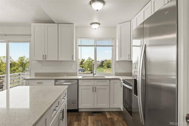kitchen featuring appliances with stainless steel finishes, a sink, white cabinets, and dark wood finished floors