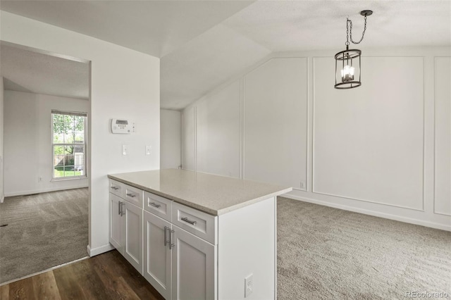 bonus room with dark colored carpet, a decorative wall, a chandelier, dark wood-style floors, and lofted ceiling