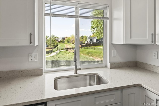 kitchen with white cabinetry and light stone countertops