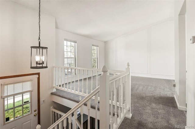 corridor with a chandelier, an upstairs landing, and carpet