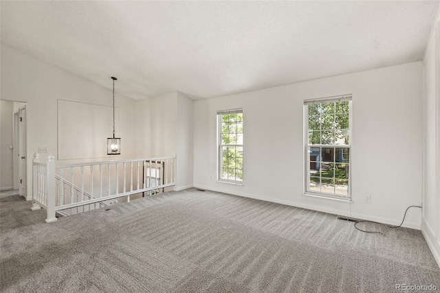 unfurnished room with carpet, healthy amount of natural light, baseboards, and vaulted ceiling
