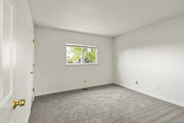carpeted empty room featuring a textured ceiling and baseboards