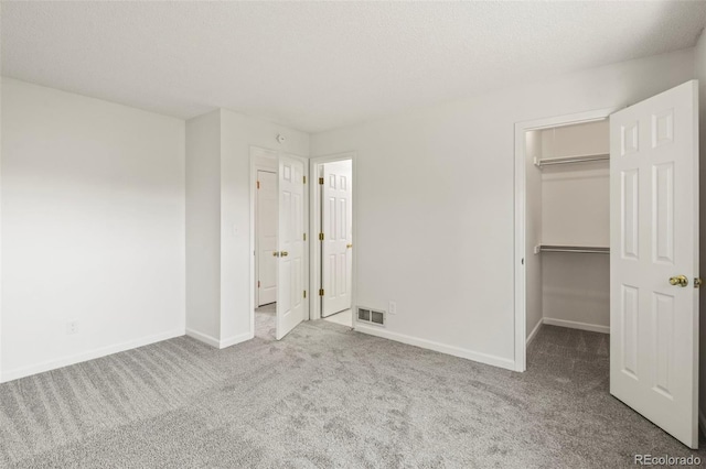 unfurnished bedroom featuring carpet, baseboards, a walk in closet, and a closet