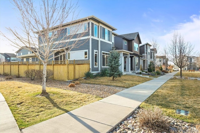 view of side of home with a residential view, a lawn, and fence