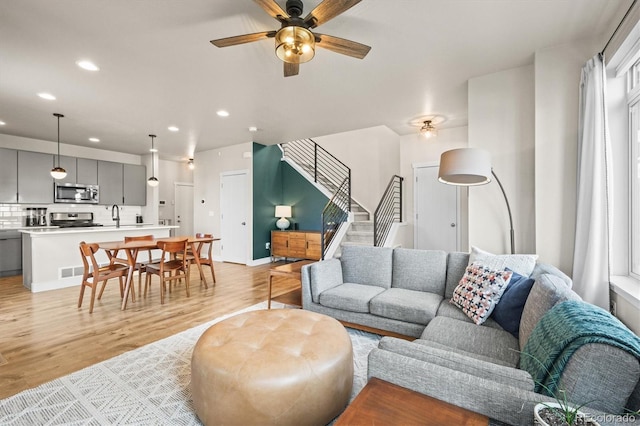 living area featuring stairs, light wood-style flooring, recessed lighting, and ceiling fan