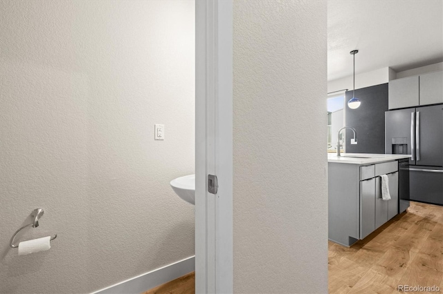 interior space with a sink, gray cabinetry, stainless steel refrigerator with ice dispenser, and light wood finished floors