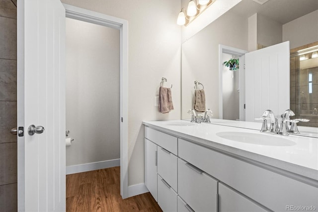 bathroom featuring double vanity, wood finished floors, baseboards, and a sink