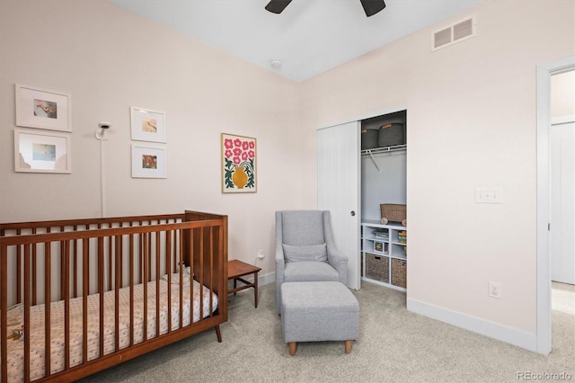 carpeted bedroom with a nursery area, baseboards, visible vents, and ceiling fan