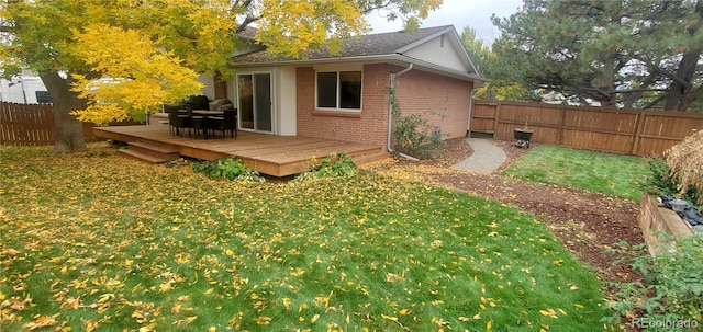 back of property with a yard and a wooden deck