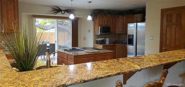 kitchen featuring backsplash, stainless steel appliances, decorative light fixtures, light stone counters, and a breakfast bar