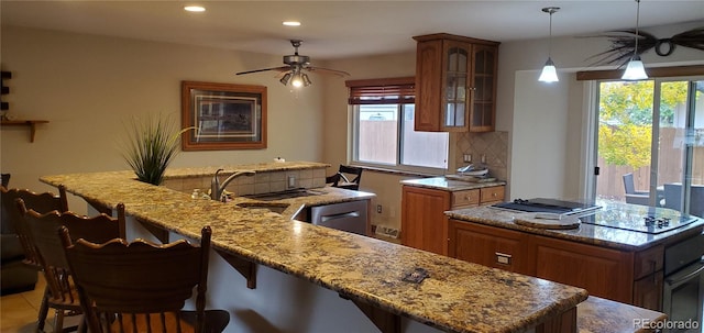 kitchen featuring stainless steel appliances, a center island, ceiling fan, decorative light fixtures, and tasteful backsplash