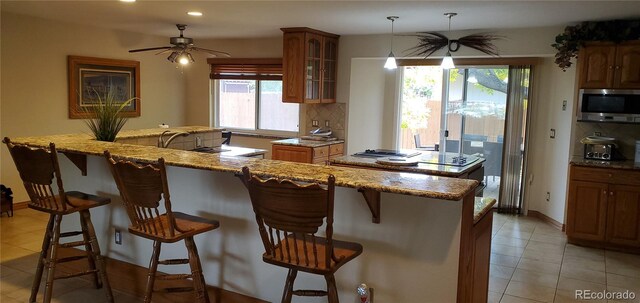 kitchen with light stone countertops, plenty of natural light, a kitchen breakfast bar, and hanging light fixtures