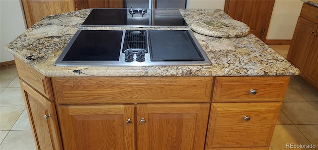 interior details featuring light stone countertops, a center island, and light tile patterned flooring