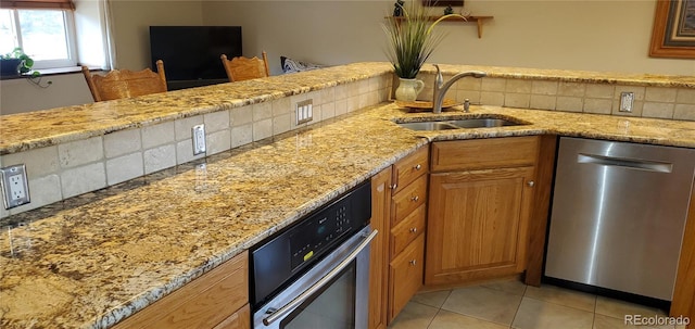 8120 S Jay Dr, Littleton, CO 80128 - kitchen featuring appliances with stainless steel finishes, a sink, brown cabinetry, light stone counters, and light tile patterned flooring