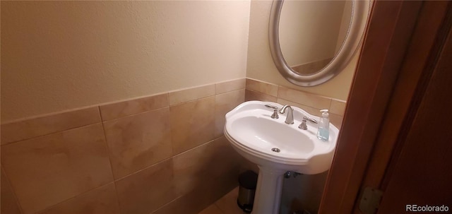 bathroom featuring tile walls and sink