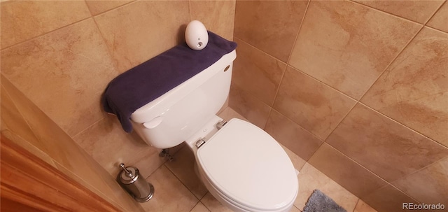 interior space featuring tile walls and toilet