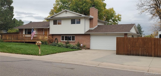 tri-level home featuring a front yard, a garage, and a wooden deck